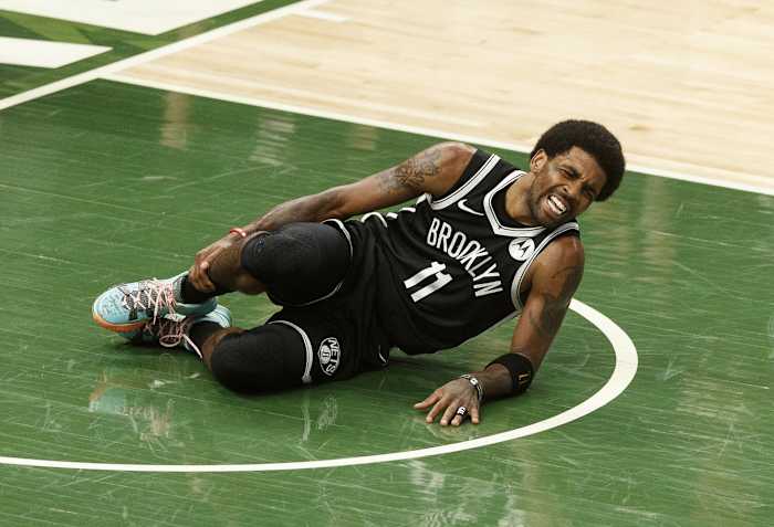Brooklyn Nets guard Kyrie Irving (11) grabs his leg after being injured during the second quarter against the Milwaukee Bucks